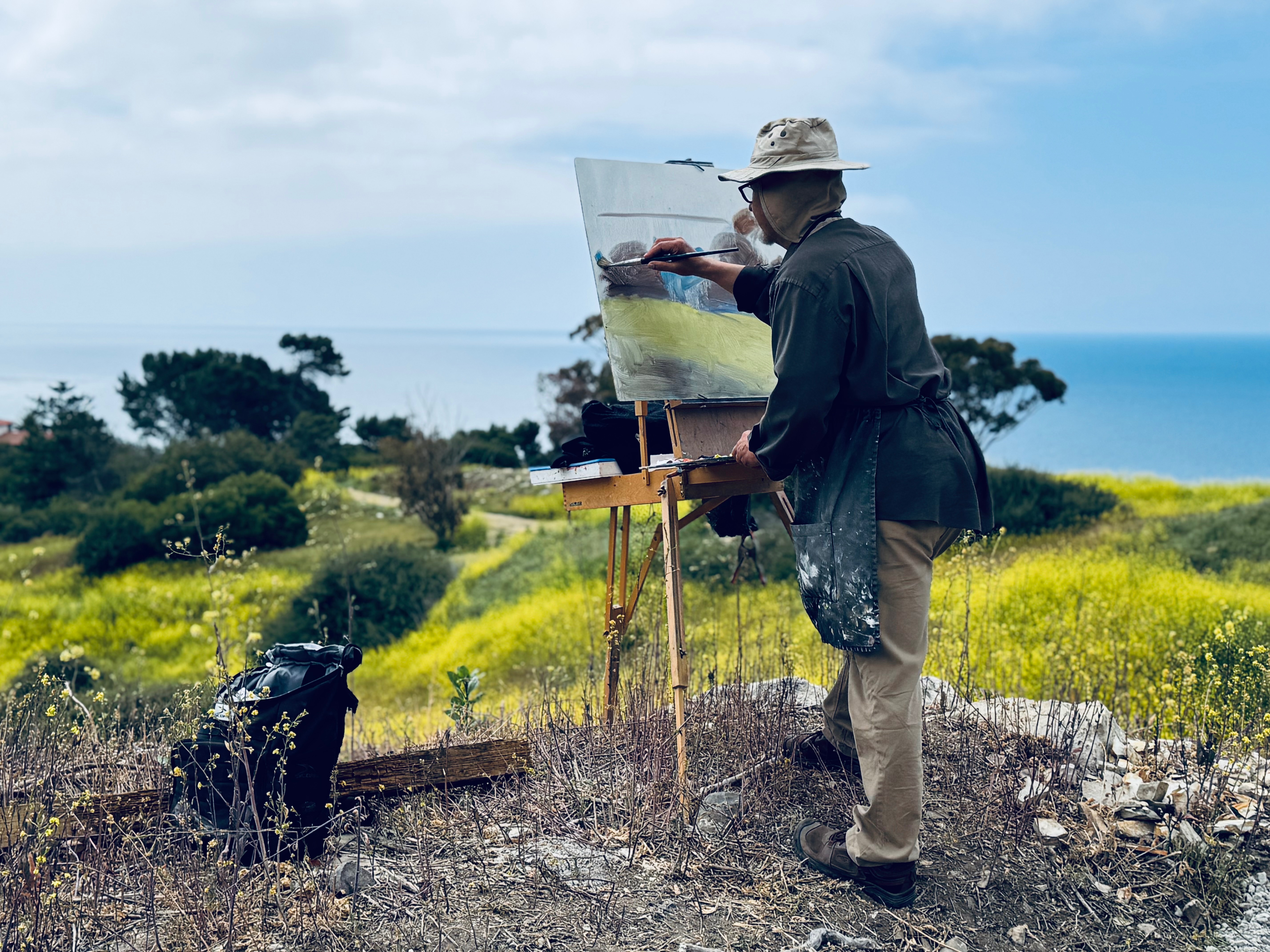 Twilight meditation scene with Buddha statue on wooden deck surrounded by flowering plants overlooking Pacific Ocean