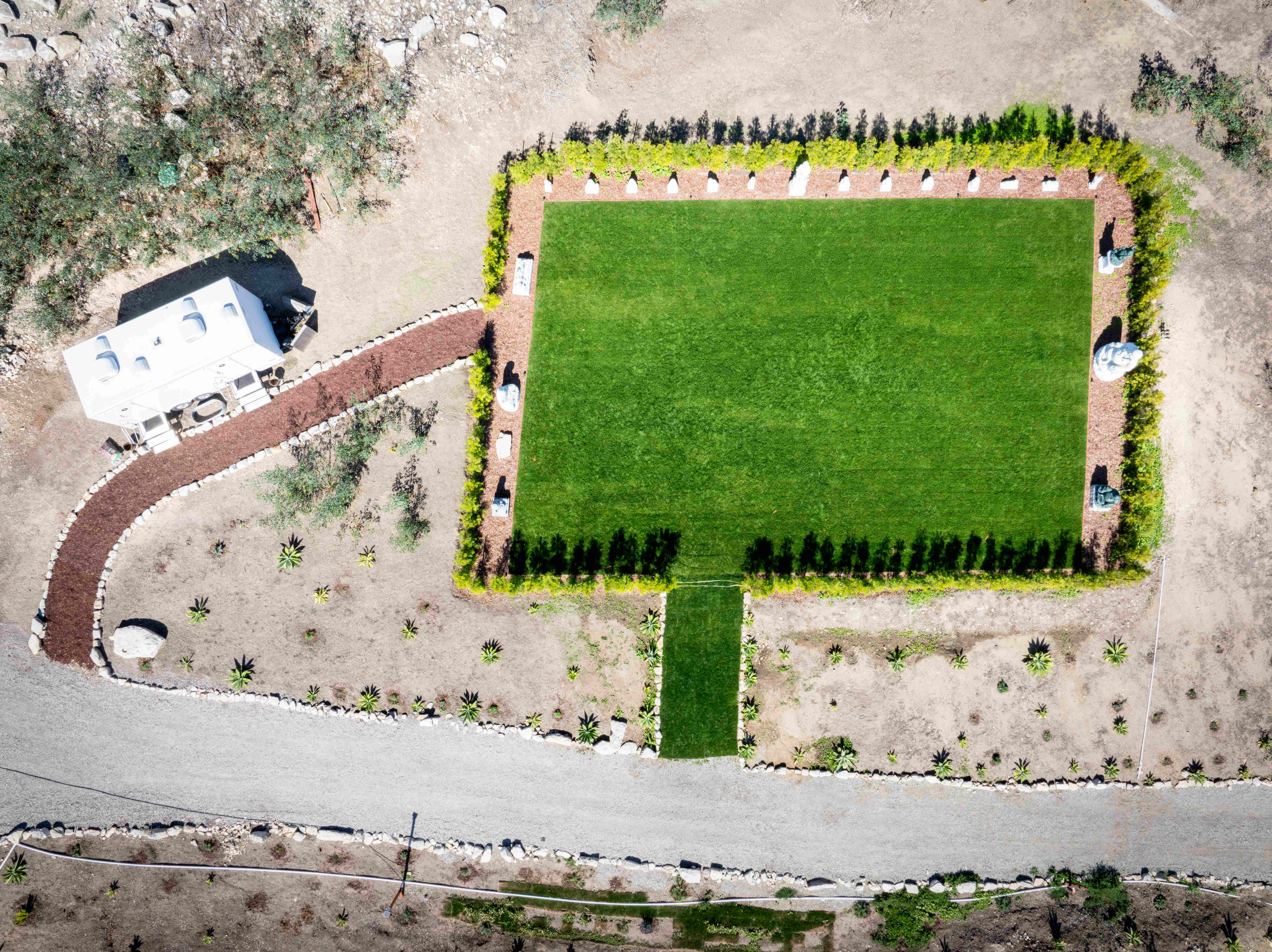 Aerial bird's-eye view of Plaza Sunshine showing pristine rectangular green lawn bordered by cypress trees and white Buddha statues